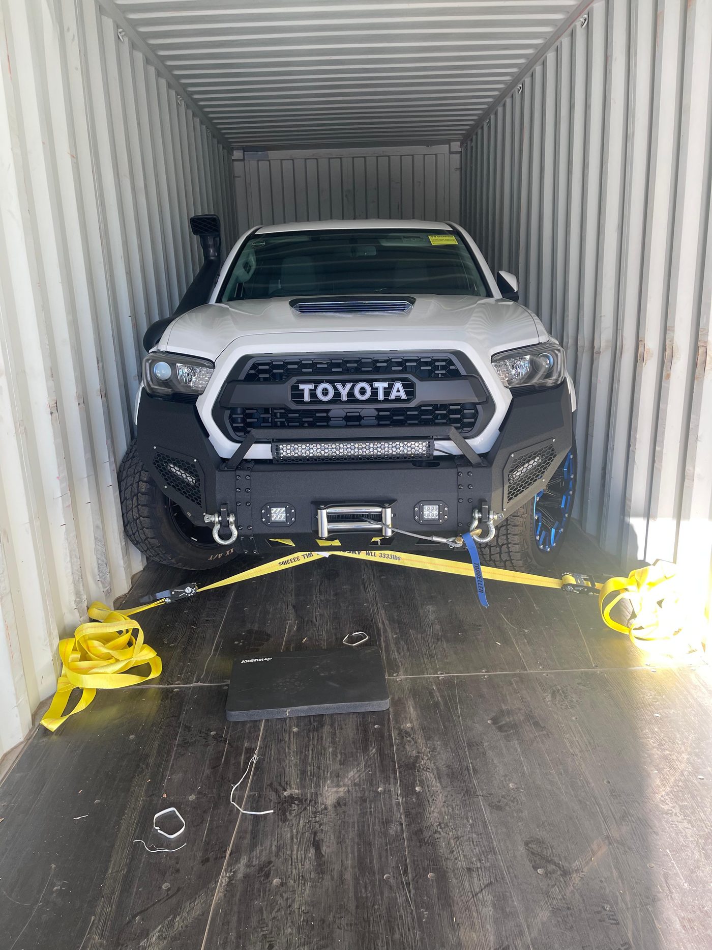 Toyota Tacoma secured inside shipping container with straps